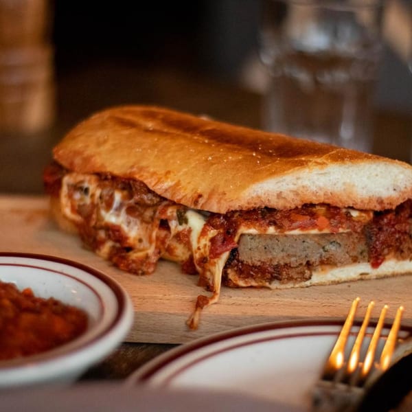 A delicious meatball sub with melted cheese and marinara sauce on a wooden board.